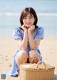 A woman sitting on the beach with a basket.