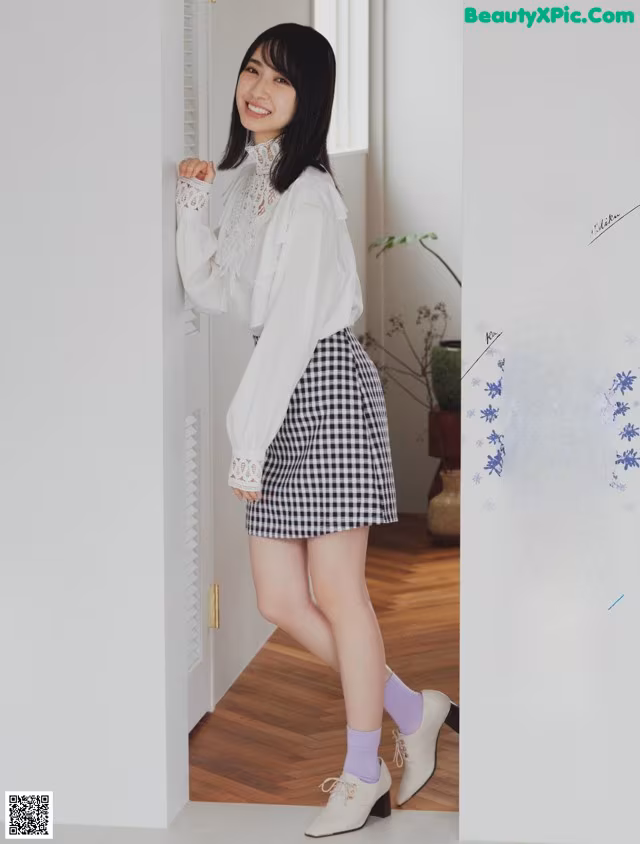 A woman in a white blouse and black and white checkered skirt.