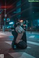 A woman in a black cat costume is sitting on the street.