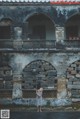 A woman standing in front of an old building.