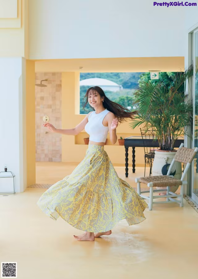 A woman in a white top and a yellow skirt dancing.