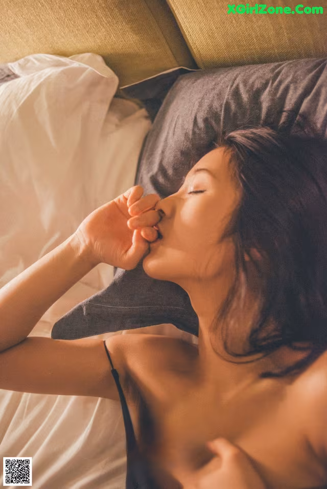 A woman laying on a bed with her eyes closed.