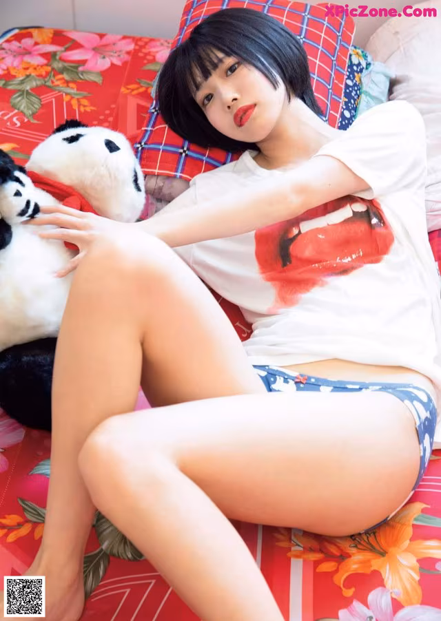 A woman laying on a bed with a teddy bear.