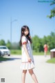 A woman in a white dress is walking down the street.