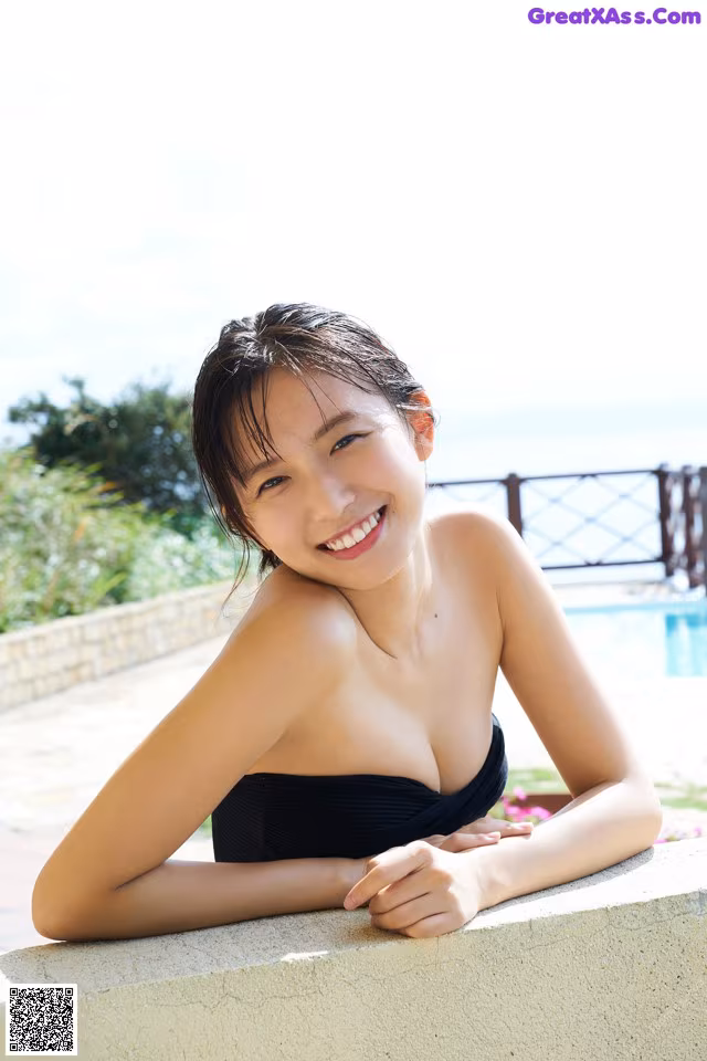 A woman in a black bathing suit leaning against a wall.