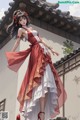 A woman in a red and white dress standing in front of a building.