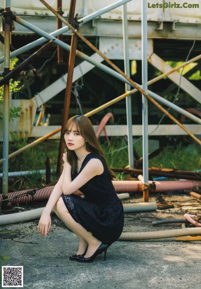 A woman in a black dress sitting on the ground.