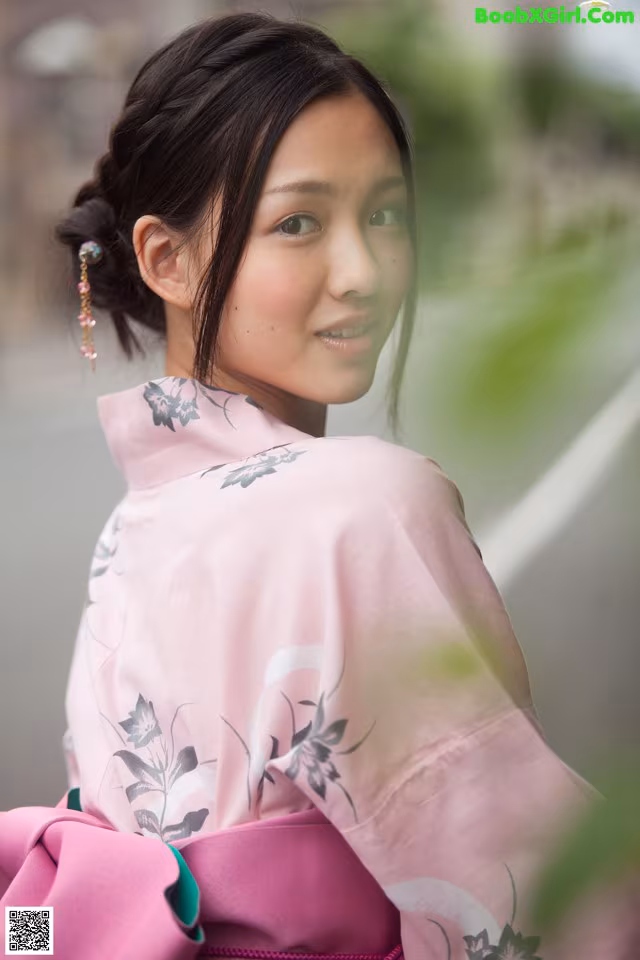 A woman in a pink kimono is posing for a picture.