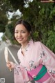 A woman in a pink kimono holding a fan.