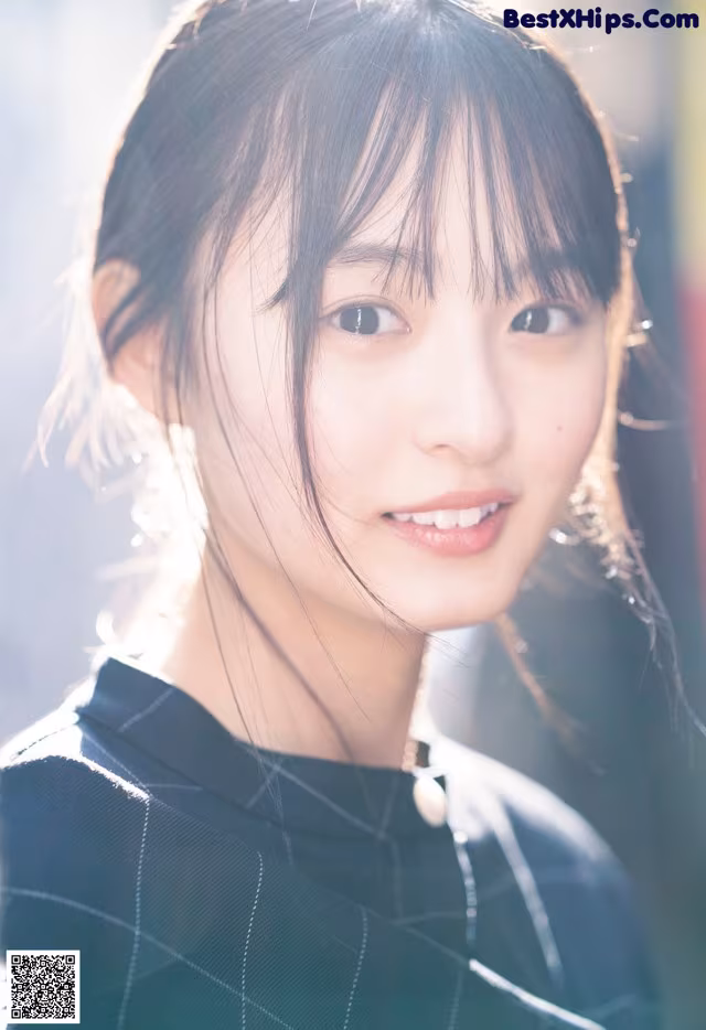 A woman with long black hair and bangs smiles at the camera.