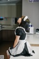 A woman in a maid outfit sitting on a kitchen counter.