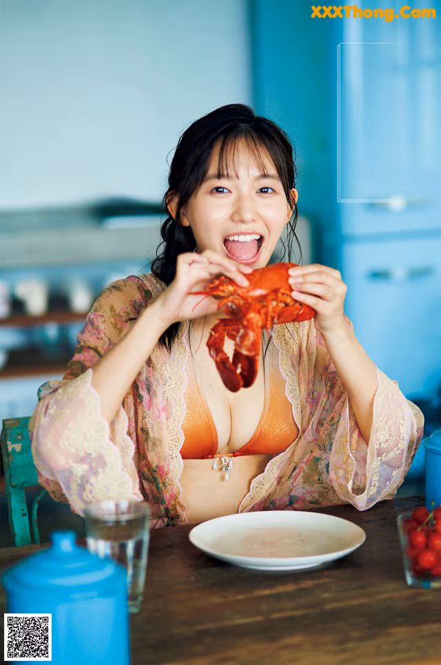 A woman sitting at a table eating a lobster.