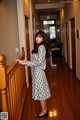 A woman standing on a wooden railing in a hallway.