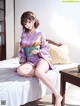 A woman in a kimono sitting on a bed.